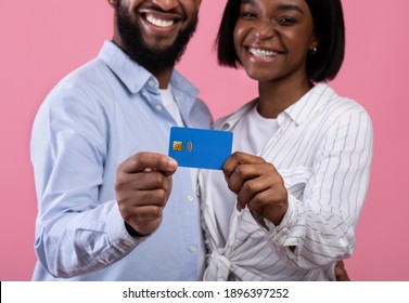 Cropped View Of Black Married Couple Holding Credit Card On Pink Studio Background, Focus On Hands. Romantic Guy And His Girlfriend Promoting Contactless Shopping For Valentine's Presents