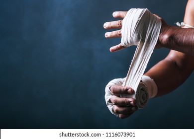 Cropped view of boxer wrapping his hands in dark gray backdrop.Copy space - Powered by Shutterstock