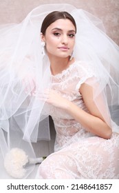 Cropped View Of Bride Sitting On Floor. A Glamorous Updo Is An Opportunity To Show Off A Dramatic Set Of Statement Vintage Style Earrings. Portrait Of Bride In Veil And Ace Gown. Studio Indoor Image 