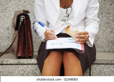 Cropped View Of Business Woman Eating Sandwich Outdoors. Selective Focus On Hand And Pen