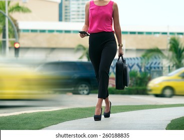 Cropped View Of Business Woman Walking In City Street With Laptop Bag, Chatting On Mobile Phone And Going To Work In The Morning