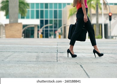 Cropped view of business woman walking in city street with laptop bag, commuting and going to work in the morning. Copy space, waist down