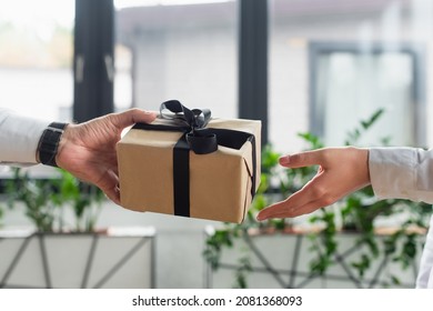 cropped view of businessman giving gift box to woman in office, anti-corruption concept