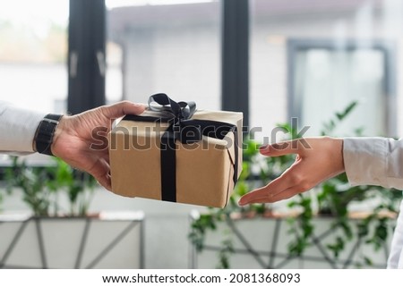 cropped view of businessman giving gift box to woman in office, anti-corruption concept