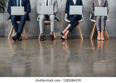 cropped view of businesspeople sitting on chairs and using laptops in waiting hall - Shutterstock ID 1281084199