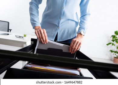 Cropped View Of Businesswoman Taking Folder With Dossier From Open Cabinet Driver In Office