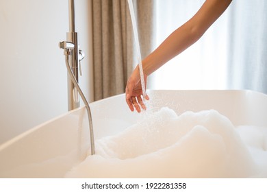 Cropped view of the calm pretty multiracial brunette female checking the water temperature with her hand before the relaxing in morning at home and having bath. Skin care concept - Powered by Shutterstock