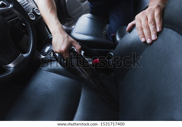 cropped\
view of car cleaner vacuuming drivers seat in\
car