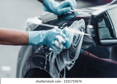 cropped view of car cleaner washing car with sponge and detergent