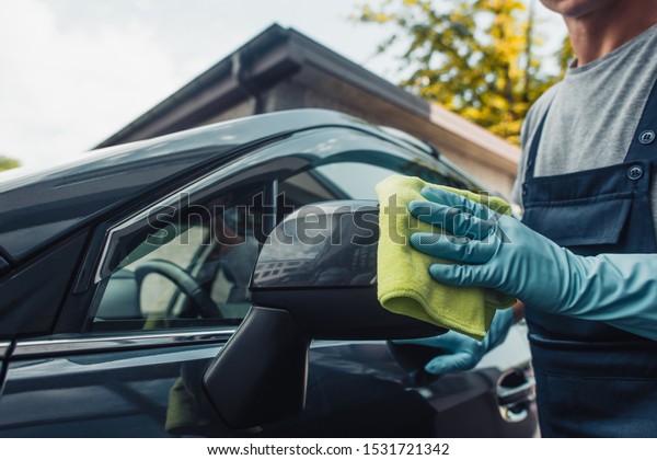 cropped\
view of car cleaner wiping side mirror with\
rag