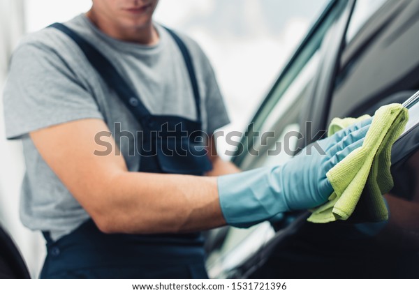 cropped view of
car cleaner wiping car with
rag