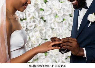 Cropped View Of Cheerful African American Man Putting Wedding Ring On Finger Of Bride Near Flowers 