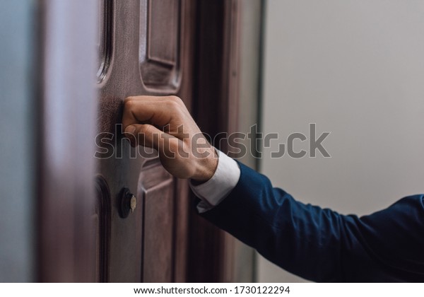 Cropped view\
of collector knocking on door with\
hand