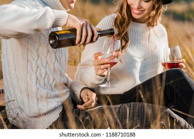 cropped view of couple pouring red wine on meadow - Powered by Shutterstock