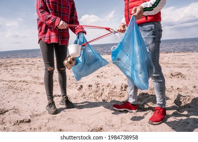 Cropped View Of Couple With Trash Bags And Grabbers Picking Up Garbage On Sand 