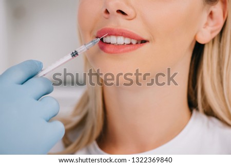 cropped view of dentist giving local anesthesia injection to woman
