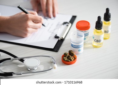 cropped view of doctor writing prescription near dried weed, bottles with cbd and medical cannabis lettering