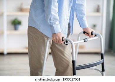 Cropped View Of Elderly Man Walking With Frame At Home, Closeup. Unrecognizable Senior Male Using Medical Equipment To Move Around His House. Disabled Older Person In Need Of Professional Help