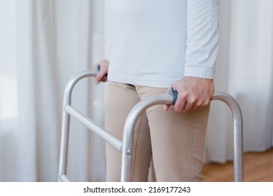 Cropped View Of Elderly Man Walking With Frame At Home, Closeup. Young Male Asian Using Medical Equipment To Move Around His House. Disabled Older Person In Need Of Professional Help