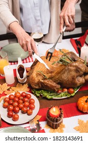 Cropped View Of Elderly Woman Cutting Turkey Near Decorations On Table