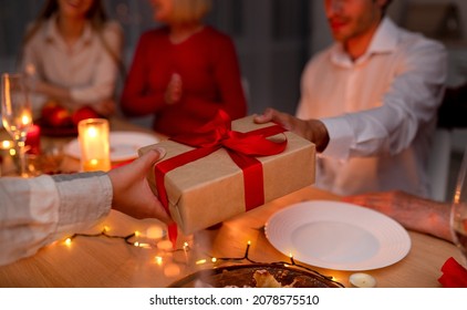 Cropped view of father giving wrapped gift box to his son during festive dinner at home, closeup. Unrecognizable dad and his child exchanging presents while celebrating holiday with family - Powered by Shutterstock