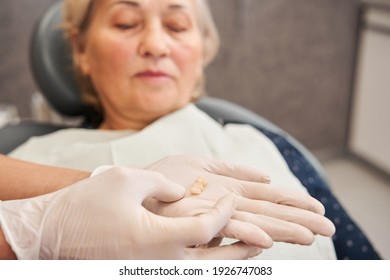 Cropped view of the female dentist holding tooth after extraction. Hand of doctor with loose tooth. Dentistry concept. Woman looking at her miss teeth. Focus at the tooth. Stock photo - Powered by Shutterstock