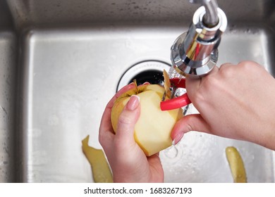 Cropped View Of Female Hands Peeling Apple Over Food Waste Disposer Machine