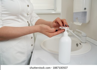 Cropped view of female hands pressing on soap bottle before washing hands in a sink