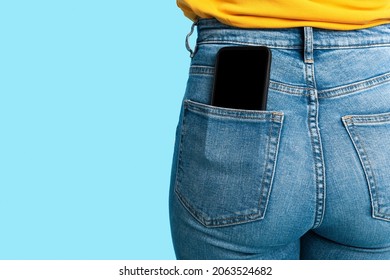 Cropped view of female having cellphone with blank screen in jeans pocket on blue studio background, mockup for mobile app or website. Free space for your advertisement template - Shutterstock ID 2063524682