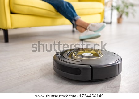 Cropped view of female legs with robotic vacuum cleaner on floor in living room Stock photo © 
