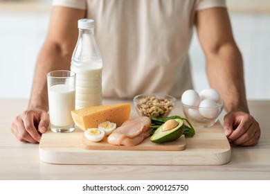 Cropped view of fit young guy standing near wholesome protein products at kitchen, closeup. Unrecognizable sporty man offering healthy nutrition for muscle gain or weight loss