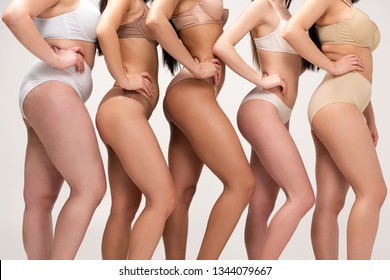 cropped view of five multiethnic women in underwear posing with hands on hips isolated on grey, body positivity concept