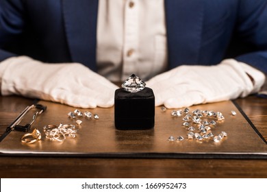 Cropped view of gemstone near jewelry on board and jewelry appraiser at table isolated on black