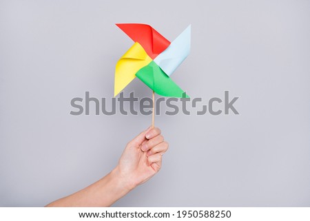 Cropped view of hand holding handicraft carton wind mill isolated over grey pastel color background