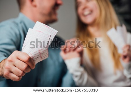 cropped view of happy man and woman holding hands while holding lottery tickets