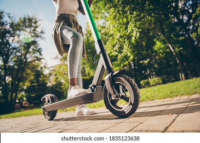 Cropped view of her she teenage teen trendy skinny slim fit hipster girl's legs riding kick scooter spending free time sunny day having fun, activity sport in forest wood outdoor youth hobby