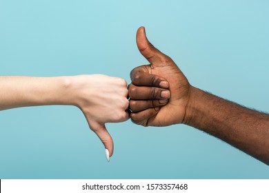 cropped view of interracial couple showing thumbs up isolated on blue