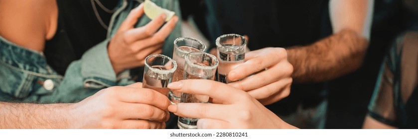 Cropped view of interracial friends holding glasses of tequila in bar, banner - Powered by Shutterstock