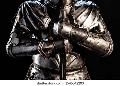 cropped view of knight in armor holding sword isolated on black 
