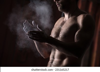 Cropped View Of A Male Gymnast Dusting His Hands With Chalk