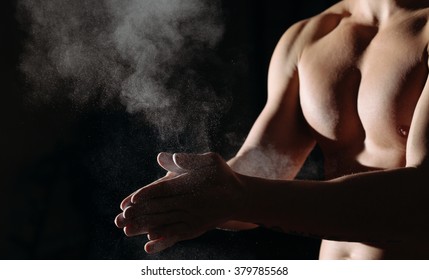 A Cropped View Of A Male Gymnast Dusting His Hands With Chalk