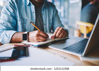 Cropped view of male hands with pencil writing down list to do in notepad sitting at desktop with laptop computer with wireless internet.Designer drawing sketch in notebook working on freelance - Powered by Shutterstock