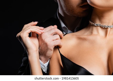 cropped view of man in black blazer and white shirt gently undressing woman isolated on black