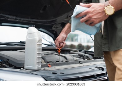 Cropped View Of Man Checking Oil Of Engine Near Bottle On Car