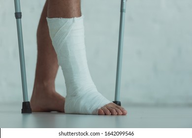 Cropped View Of Man With Gypsum On Leg Holding Crutches