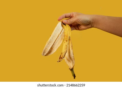 cropped view of man holding banana peel in hand isolated on yellow - Powered by Shutterstock