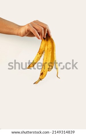 cropped view of man holding banana peel in hand isolated on white background.