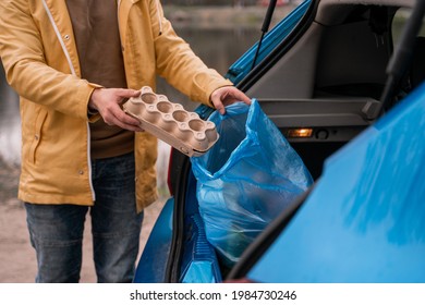 Cropped View Of Man Holding Carton Container Near Blue Trash Bag In Car 