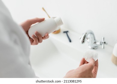 Cropped View Of Man Holding Cosmetic Container And Cotton Pad Near Blurred Sink