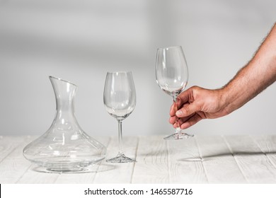 Cropped View Of Man Holding Empty Wine Glass Above Wooden Surface In Restaurant